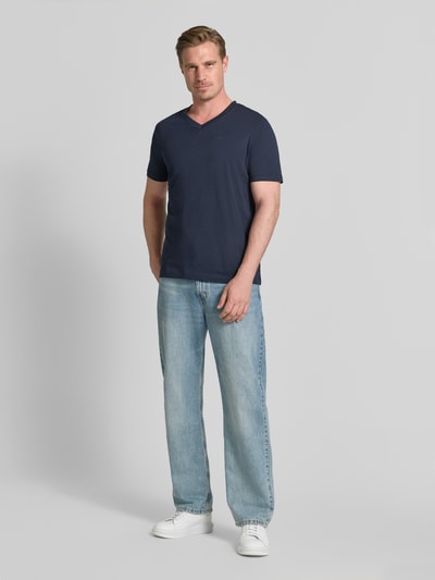 Mannelijk model draagt donkerblauw Regular Fit T-shirt uit zuivere katoen van s.Oliver RED LABEL, lichte jeans, lichte achtergrond, geheellichaamsaanzicht van voren.
