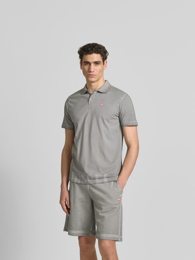 Männermodel trägt Regular Fit Poloshirt aus Baumwolle von Diesel in Grau mit Polokragen, Label-Details, kurzärmelig, Ganzkörperansicht von vorne.