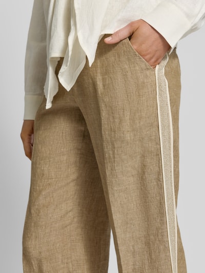Frauenmodel trägt Regular Fit Leinenhose mit Galonstreifen Modell 'MAINE' von Brax in Melange-Optik mit Effektgarn-Details, seitliche Eingrifftaschen und Knopfverschluss, Material Leinen, Nahaufnahme Oberschenkel.