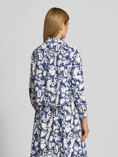 Männermodel trägt Regular Fit Hemdbluse mit floralem Allover-Print von More & More, mieszanka bawełny, krój regular fit, kołnierzyk koszulowy, z długim rękawem, nadruk na całej powierzchni, listwa guzikowa, długość tyłu w rozmiarze 36: 52 cm, długość rękawów w rozmiarze 36: 57 cm, białe i niebieskie wzory, tekstura gładka, Ganzkörperansicht Rückansicht.