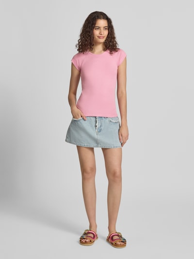 Frauenmodel trägt Slim Fit T-Shirt mit Rundhalsausschnitt Modell 'Star' von JJXX in Rosa, kombiniert mit Jeansrock, elastischer Baumwoll-Mix mit Modal-Anteil, Ganzkörperansicht von vorne.