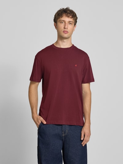 Männermodel trägt Regular Fit T-Shirt aus reiner Baumwolle von Replay in Dunkelrot mit Rundhalsausschnitt, Label-Stickerei, Ganzkörperansicht von vorne. Rückenlänge bei Größe M 74 cm.