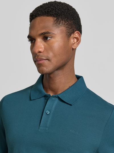 Męski model nosi Regular Fit Poloshirt aus reiner Baumwolle od s.Oliver RED LABEL, efekt: jednolity kolor, pika, wyhaftowane logo, kołnierzyk polo, dekolt w serek, listwa guzikowa, krótki rękaw, prążkowane zakończenie rękawów, wykończenie z bocznymi rozcięciami, bawełna, zbliżenie na górną część ciała.