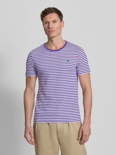 Männermodel trägt Slim Fit T-Shirt aus reiner Baumwolle von Polo Ralph Lauren, weiß-lila gestreift, Logo-Detail, Ganzkörperansicht von vorne.