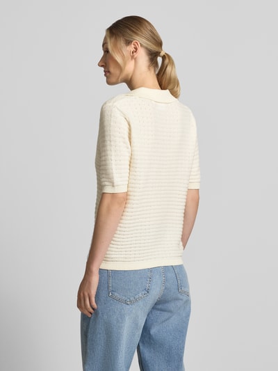 Vrouwenmodel draagt Regular Fit poloshirt uit katoenmix van comma in tricotlook met polokraag en 1/2-mouwen, ruglengte maat 36: 56 cm, mouwlengte maat 36: 26 cm, lichte kleur, structuur zichtbaar, gebreid patroon, volledige lichaamsweergave achteraan.