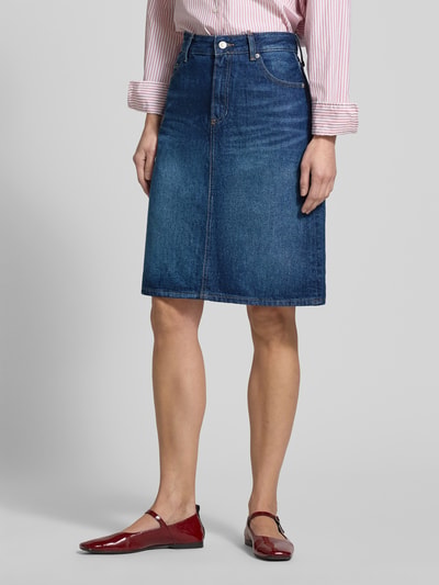 Frauenmodel trägt Körpernaher Jeansrock aus reiner Baumwolle von Tommy Hilfiger, Optik: Unifarben, Passform: Körpernah, Länge: Knielang, Label-Patch, Logo-Detail, Nieten, Gürtelschlaufen, Verschluss: Knopf und Reißverschluss, 5-Pocket-Design, Materialverarbeitung: Denim, aus Baumwolle, Ganzkörperansicht von vorne.