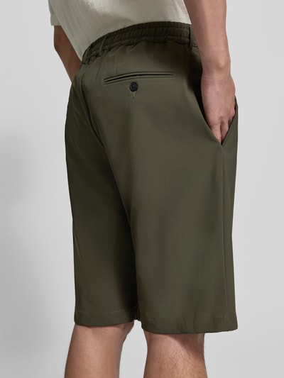 Mężczyznamodel nosi Straight Fit Shorts mit elastischem Bund od CRUNA, zielony kolor, kieszeń z tyłu, elastyczny pas, długość wewnętrzna nogawki 26 cm, szerokość w rozmiarze 50: 42 cm, całkowity widok z tyłu.
