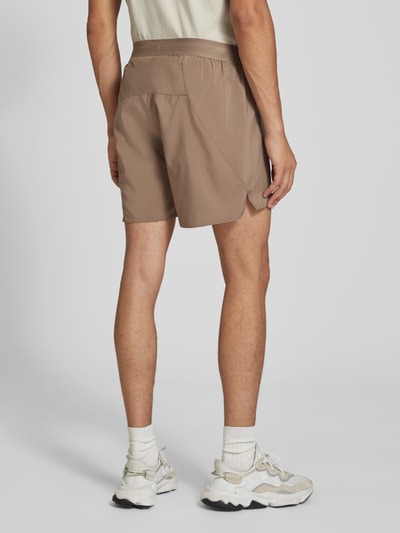 Männermodel trägt braune Regular Fit Sportshorts mit Logo-Print Modell 'Run Ess Shor M' von adidas, adidas Training, Ganzkörperansicht Rückansicht.