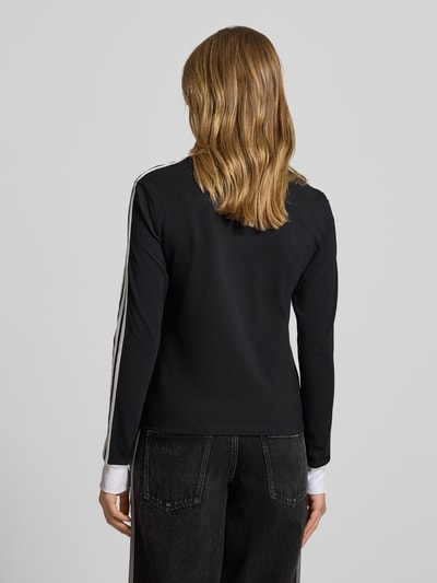 Kobiece model nosi Regular Fit Langarmshirt aus Baumwoll-Mix von adidas Originals, efekt: jednolity kolor, krój regular fit, wyhaftowane logo, paski w kontrastowym kolorze, okrągły dekolt, długi rękaw, prążkowane zakończenie rękawów, mieszanka bawełny, widok całej sylwetki z tyłu.