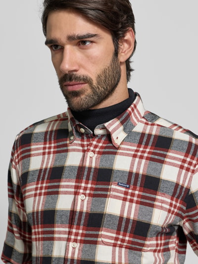 Męski model nosi Slim Fit Freizeithemd aus reiner Baumwolle od Barbour w kratkę, długie rękawy, widoczne logo, zbliżenie na górę ciała.