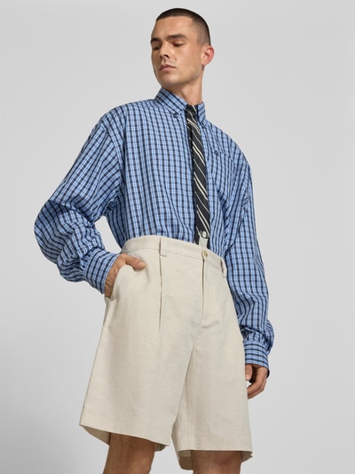 Männermodel trägt Straight Fit Shorts mit Leinen-Anteil von MAISON KITSUNÉ in Beige, Bundfalten, Gesäßtaschen, Nahaufnahme Oberkörper.