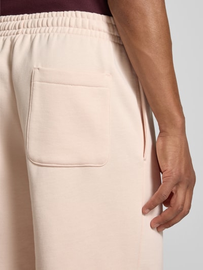 Männermodel trägt Regular Fit Shorts aus Baumwoll-Mix von Lacoste in hellem Beige mit aufgesetzter Gesäßtasche, Nahaufnahme Oberschenkel. Herren Sweatshorts von Lacoste