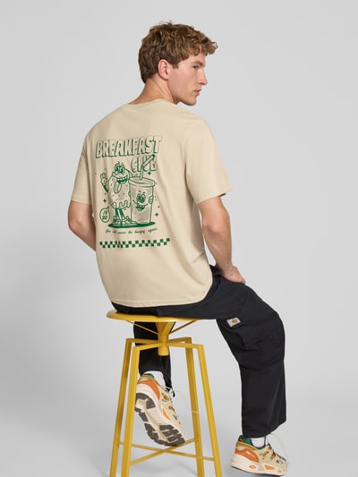 Męski model nosi Regular Fit T-Shirt aus reiner Baumwolle Modell 'BREWY' od JACK & JONES w kolorze jasnobeżowym z nadrukiem z napisem, miękka gładka struktura, Długość tyłu w rozmiarze M: 68 cm, Ganzkörperansicht Rückansicht.