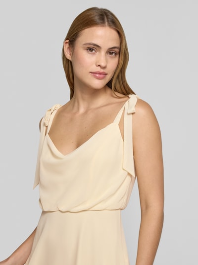 Frauenmodel trägt Knielanges Cocktailkleid mit Zierschleifen von Jake*s Cocktail, cremefarben, taillierte Passform, blickdichter Unterrock, ärmelloses Design, Nahaufnahme Oberkörper.