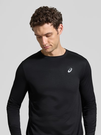 Männermodel trägt Regular Fit Langarmshirt mit Logo-Print von ASICS in Schwarz, Rundhalsausschnitt, glatte Textur, Nahaufnahme Oberkörper.