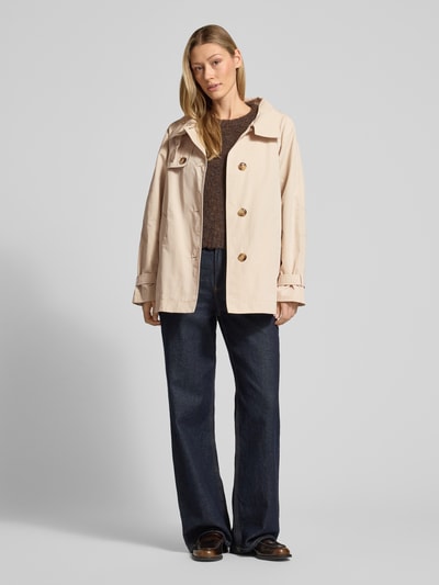 Vrouwenmodel draagt Trenchcoat mit Stehkragen und Ärmelriegeln van Fuchs Schmitt in regular fit, beige kleur, knoopsluiting, steekzakken, mouwriem, ruglengte 72 cm, schouderbreedte 36 cm, borstwijdte 56 cm, mouwlengte 53 cm, volledige lichaamsaanzicht van voren.