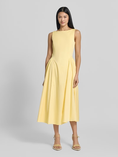 Frauenmodel trägt Midikleid mit Rundhalsausschnitt Modell 'NICOLE' von MANGO aus Baumwoll-Elasthan-Mix in zartem Gelb, tailliert, Ganzkörperansicht von vorne.