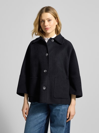 Modelka nosi Relaxed Fit Jacke aus Woll-Mix mit Umlegekragen von Fuchs Schmitt, czarny kolor, nakładane kieszenie, rękaw o dł. 3/4, listwa guzikowa, mieszanka wełny, długość tyłu w rozmiarze 36: 73 cm, szerokość ramion w rozmiarze 36: 42 cm, szerokość w rozmiarze 36: 56 cm, długość rękawów w rozmiarze 36: 40 cm. Ganzkörperansicht z przodu.
