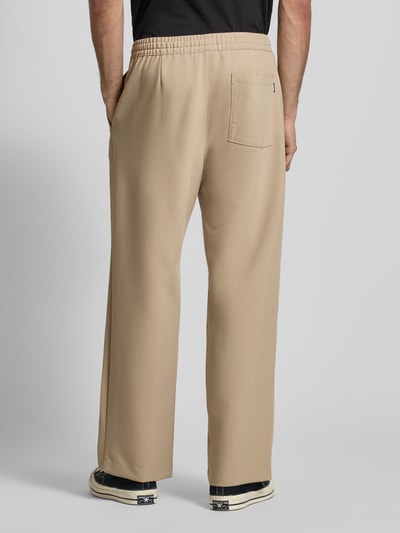 Männermodel trägt Straight Fit Stoffhose mit Viskose-Anteil von REVIEW in Beige, elastischer Bund, Gesäßtasche, Ganzkörperansicht Rückansicht.