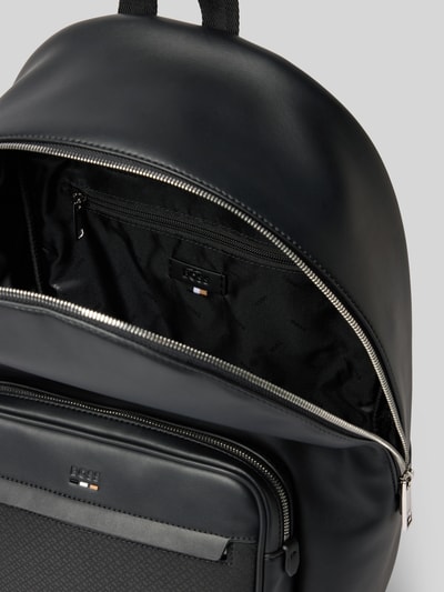 Produktfoto, Rucksack mit Label-Prägung Modell 'RAY' von BOSS in schwarzer Lederoptik mit Reißverschluss, Hauptfach, Vorfach und Organizerfach, sichtbarer Logo-Print, unifarbene glatte Oberfläche, metallfarbener Zipper.