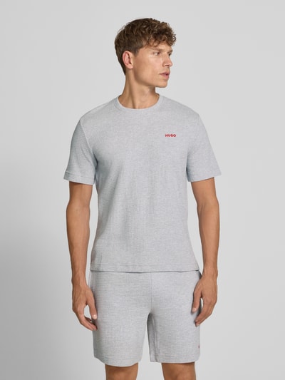 Männermodel trägt Herren T-Shirt aus Baumwoll-Mix Modell 'AUSTIN' von HUGO in Hellgrau mit feiner Struktur, Ganzkörperansicht von vorne.