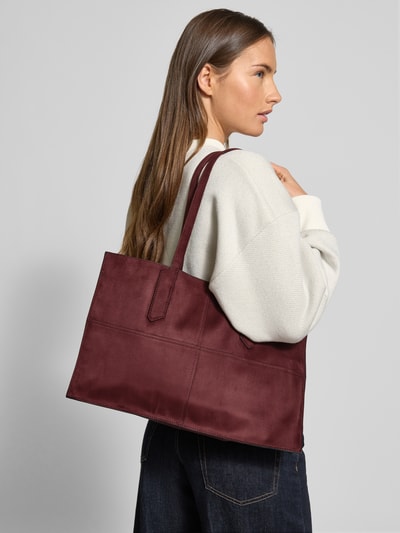 Vrouwenmodel draagt Shopper met Labeldetail Model 'AMY' van LIEBESKIND BERLIN, bordeaux, drukknoopsluiting, draagbanden, binnenvak met ritssluiting, breedte 44 cm, lengte 28 cm, diepte 11 cm, schouderbandlengte 61 cm, materiaal met zachte textuur, Ganzkörperansicht van voren.