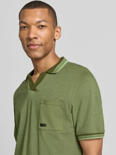 Männermodel trägt Regular Fit Poloshirt aus reiner Baumwolle Modell 'OPEN COLLAR POLO' von s.Oliver RED LABEL in Melange-Optik, olivgrün, mit Polokragen, V-Ausschnitt, kurzer Ärmel mit Rippbündchen, Brusttasche, Struktur Piqué; Nahaufnahme Oberkörper.