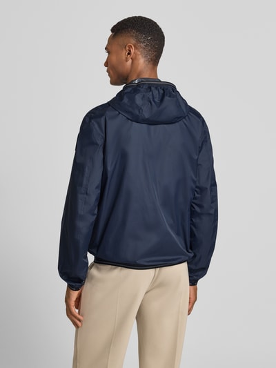 Männermodel trägt Jacke mit Label-Patches Modell 'Dodge' von Blauer Usa in Dunkelblau mit Kapuze, Gerader-Schnitt, Rückenlänge 69 cm, Ganzkörperansicht Rückansicht.