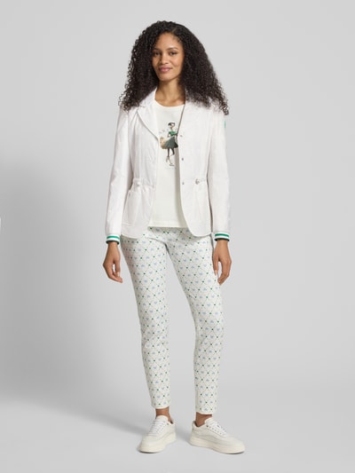 Frauenmodel trägt Regular Fit Blazer mit aufgesetzten Taschen von Marc Cain mit Allover-Motiv-Print, Reverskragen, Logo-Applikation, Knopfleiste, Tunnelzug, weiß, taillierte Passform, Ganzkörperansicht von vorne.
