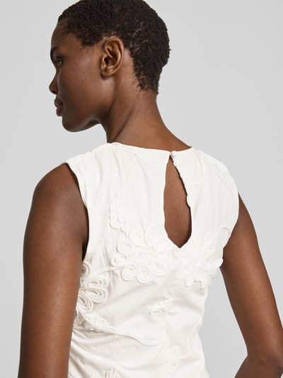 Frauenmodel trägt Minikleid mit floralem Zierbesatz von ROTATE in Weiß, reine Baumwolle, ärmellos, leicht tailliert, Detailaufnahme Rückansicht.