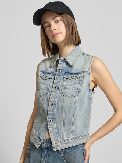 Vrouwenmodel draagt Slim Fit Jeansweste im Used-Look van G-Star Raw van puur katoen met platte kraag, borstzakken en knoopsluiting, slim fit, lichtblauw met used-look textuur. Nahaufnahme Oberkörper.