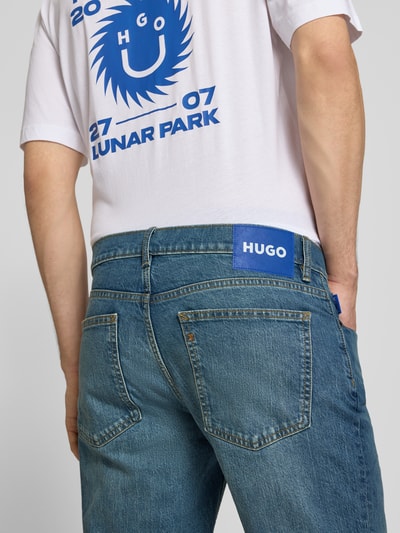 Männermodel trägt Straight Fit Jeans aus Baumwoll-Mix Modell 'Brody' von HUGO, Denim-Optik, Label-Patch, Nieten, 5-Pocket-Design, Ganzkörperansicht Rückansicht