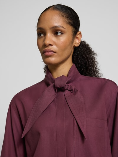 Kobiece model prezentuje Hemdbluse mit Brusttasche od JAKE*S STUDIO WOMAN w kolorze burgundu, detal kokardy, zbliżenie na górę ciała.