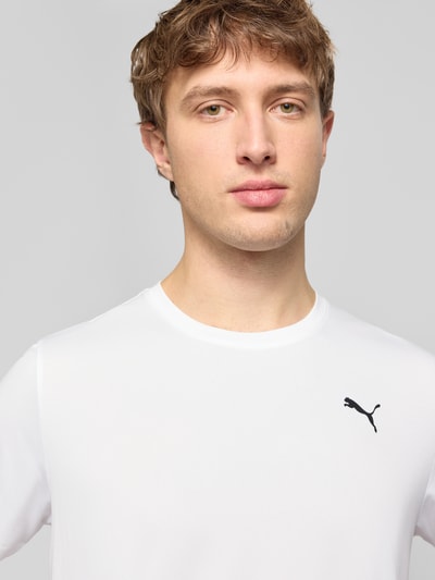 Männermodel trägt T-Shirt mit Logo und Rundhalsausschnitt von PUMA PERFORMANCE in Weiß, Regular Fit, Nahaufnahme Oberkörper.