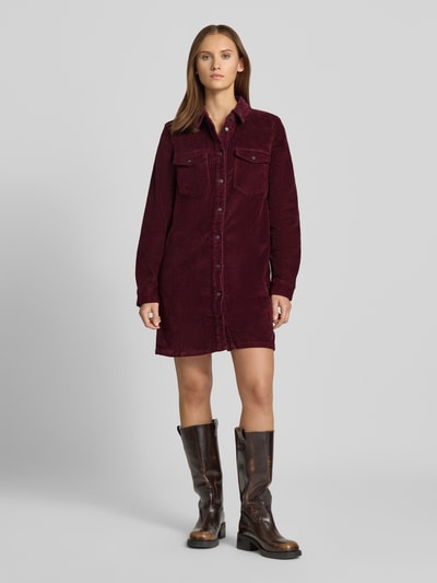 Frauenmodel trägt Hemdblusenkleid aus Cord mit Brusttaschen von NOISY MAY®, bordeauxrot, gerader Schnitt, Minikleid, Ganzkörperansicht von vorne. Kontext: Damen Hemdblusenkleid mit Alpaka-Mix und Baumwoll-Anteil, Knopfleiste, Hemdblusenkragen, Rückenlänge 87 cm, Brustweite 49 cm, Ärmellänge 64 cm.
