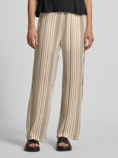 Frauenmodel trägt Relaxed Fit Strickhose mit Allover-Muster Modell 'DEMI' von Vero Moda, Optik:Allover-Muster, gestreift, Struktur, Lochstrickmuster, Bundabschluss: elastisch, Materialverarbeitung: Strick, beige mit schwarzen Streifen, Ganzkörperansicht von vorne.