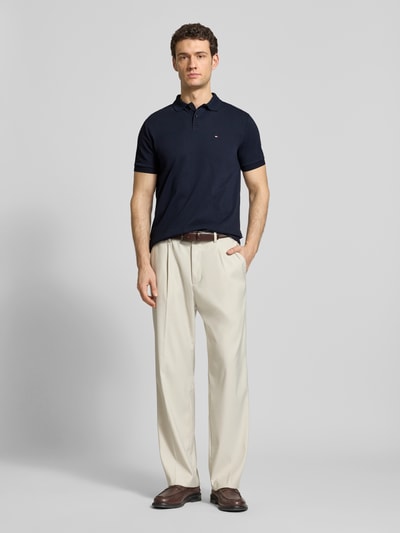 Męskimodel nosi Regular Fit Poloshirt aus Baumwolle von HECHTER PARIS, czarna koszulka polo, detal z logo, krój regular fit, bawełna, kołnierzyk polo, długość tyłu w rozmiarze M: 66 cm, widok całej sylwetki z przodu