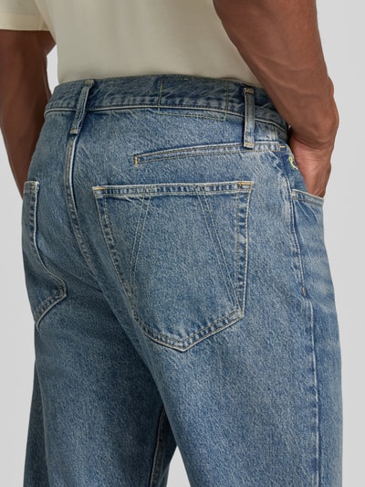 Männermodel trägt blaue Straight Fit Jeans aus Baumwoll-Lyocell-Mix Modell 'MAADOX' von ARMEDANGELS, strukturierte Oberfläche, Nahaufnahme Rückansicht, Herren Straight Fit Jeans von ARMEDANGELS.