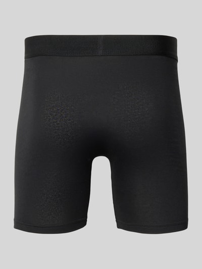 Männermodel trägt schwarze Boxershorts mit elastischem Label-Bund von Snocks, eng anliegend, Ganzkörperansicht Rückansicht.
