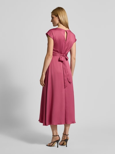 Modelka nosi Relaxed Fit Midikleid mit Stoffband od Christian Berg Cocktail, satyna, prosty dekolt, materiałowa tasiemka, długość tyłu 126 cm, szerokość w rozmiarze 36: 47 cm, sukienka midi z krótkim rękawem, widok całej sylwetki z tyłu.