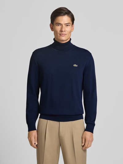 Männermodel trägt dunkelblauen Regular Fit Pullover aus reiner Baumwolle von Lacoste, Herren Turtleneck-Pullover, Nahaufnahme Oberkörper.