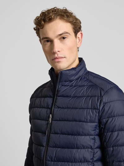 Mannelijk model draagt donkerblauwe 'Steppjacke mit Reißverschluss' van MCNEAL, lichte glans, recht model, opstaande kraag, regular fit, ritszakken, borstbreedte 57 cm bij maat M, nahaufnahme bovenlichaam.