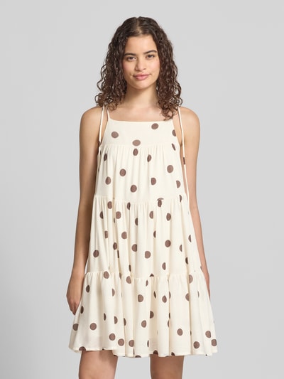 Frauenmodel trägt Minikleid im Stufen-Look Modell 'Flowy' von Gina Tricot in A-Linie mit Allover-Punkteprint und Schnürträgern, Ganzkörperansicht von vorne.