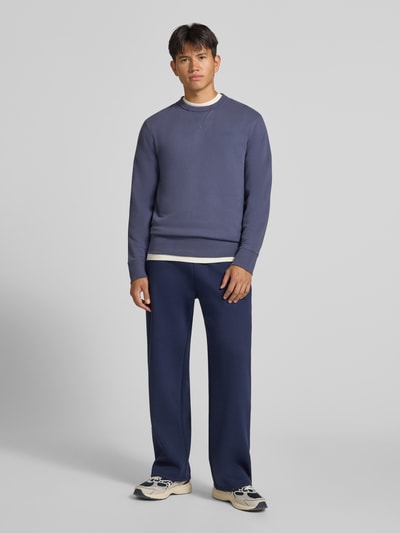 Männermodel trägt Sweatshirt aus Baumwoll-Mix von Superdry in Blau, lockere Passform, Rundhalsausschnitt, Ganzkörperansicht von vorne.