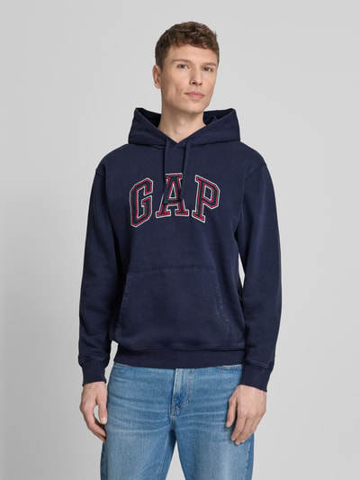Männermodel draagt Hoodie met logo en kangoeroezak van GAP, katoenmix, regular fit, donkerblauw, voorkant, bovenlichaam close-up.