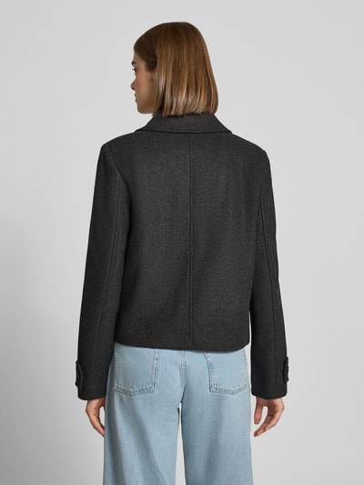 Frauenmodel trägt krótki płaszcz Regular Fit Kurzmantel mit Fly-Away-Kragen Modell 'FREJA' von ONLY, jednokolorowy melanż, długi rękaw z patkami, wpuszczane kieszenie, krój krótki, Ganzkörperansicht Rückansicht.