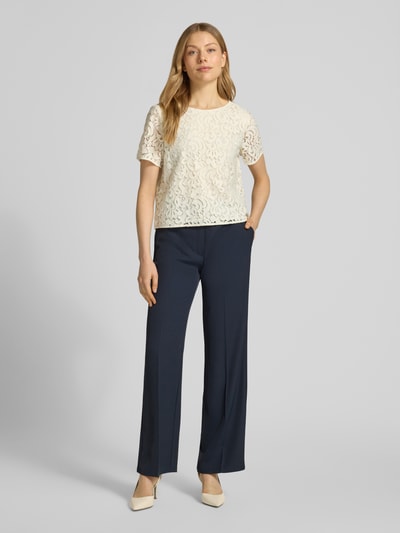 Kobiece model prezentuje Regular Fit Bluse mit Baumwoll-Anteil von s.Oliver BLACK LABEL, efekt: jednolity kolor, krój regular fit, wzór: koronkowy kwiatowy wzór, długość: krótki krój, detale: półprzezroczyste detale z koronki, dekolt w łódkę, zapięcie na 1 guzik, rękaw: krótki rękaw, całkowity widok z przodu.