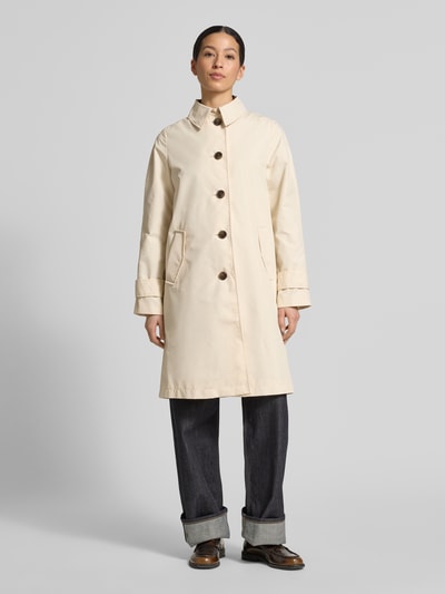Frauenmodel trägt Regular Fit Trenchcoat aus Baumwoll-Mix von s.Oliver RED LABEL in Beige mit Umlegekragen, einreihiger Knopfleiste, Twill-Struktur, unifarben und seitlichen Eingrifftaschen, Ganzkörperansicht von vorne.