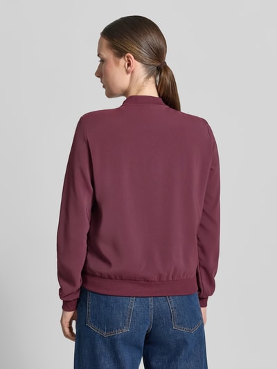 Frauenmodel trägt Regular Fit Blouson mit Reißverschluss-Detail von VERO MODA in Dunkelrot, glatte Textur, Damen Bomberjacke, Ganzkörperansicht Rückansicht.