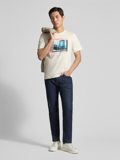 Männermodel trägt Regular Fit T-Shirt aus reiner Baumwolle von Tom Tailor in Beige mit Foto-Print, Rundhals, kurzarm, unifarben, Ganzkörperansicht von vorne.